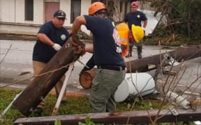 Governor Ralph Torres, (left), helps clear debris