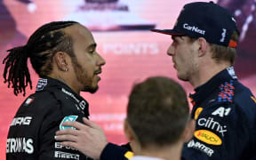 Champion Red Bull's Dutch driver Max Verstappen (right) greets second-placed Mercedes' British driver Lewis Hamilton after the Abu Dhabi F1 Grand Prix at the Yas Marina Circuit on 12 December, 2021.