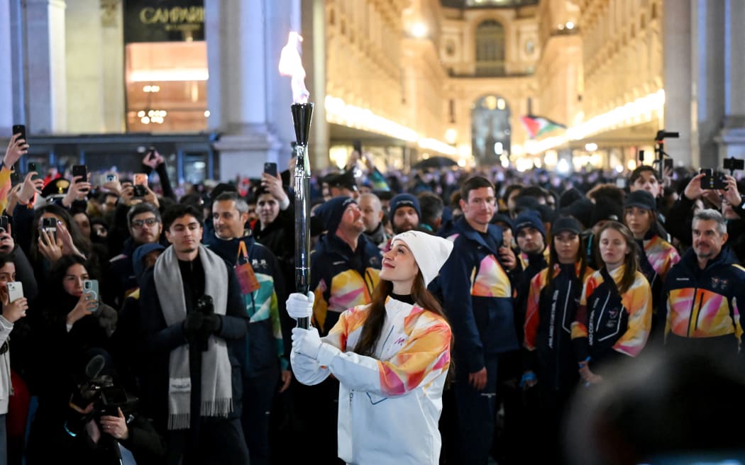 Italian ballet dancer Nicoletta Manni (C) carries the Olympic Flame as she arrives at the Piazza Duomo prior to the opening of the Milano Cortina 2026 Winter Olympic Games in Milan, Italy, on February 5, 2026. (Photo by PIERO CRUCIATTI / AFP)