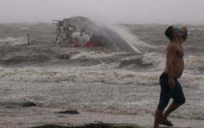 Nick Ward wears goggles to protect his eyes against the wind as he walks past a capsized boat being washed against the ashore, in St. Petersburg Florida, before Hurricane Helene has hit land, on 26 September, 2024.