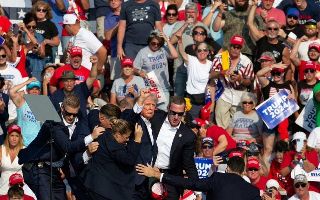 Republican candidate Donald Trump, surrounded by secret service agents as he is taken off the stage at a campaign event at Butler Farm Show Inc. in Butler, Pennsylvania, 13 July, 2024.