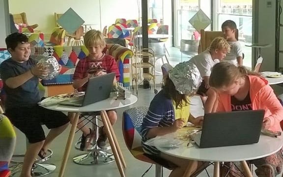 Children sitting at tables with laptops