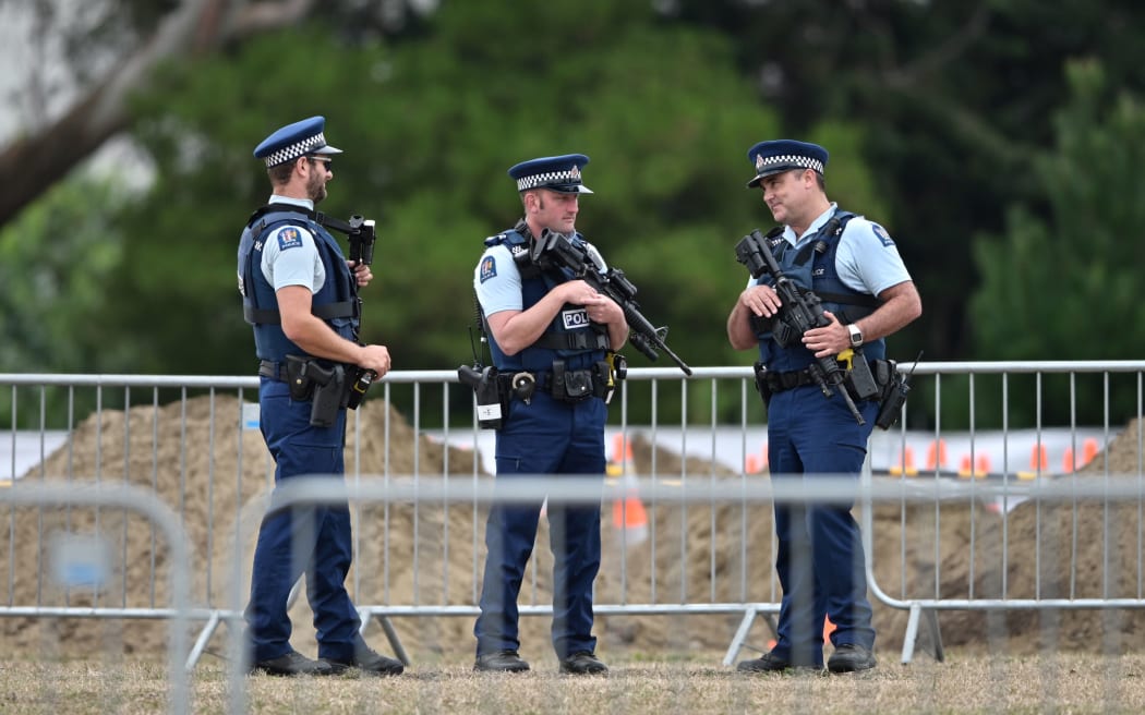 Armed police officers patrol gravesites for victims in Christchurch this morning.