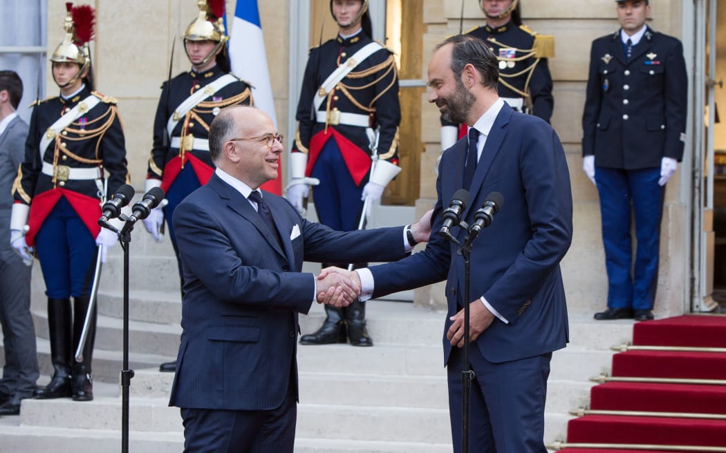 Edouard Philippe, right, shakes hands with his predecessor Bernard Cazeneuve after delivering a speech during an official handover ceremony at the Hotel Matignon.