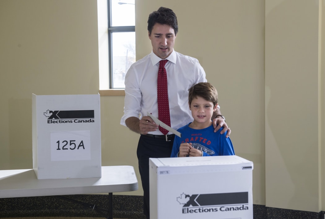 Liberal leader Justin Trudeau carries his vote to the ballot box accompanied by his son Xavier.