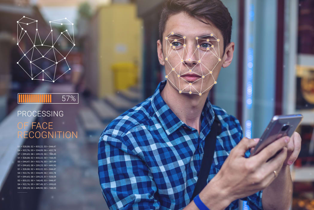 Biometric verification. Modern young man with the phone. The concept of a new technology of face recognition on polygonal grid is constructed by the points of IT security and protection