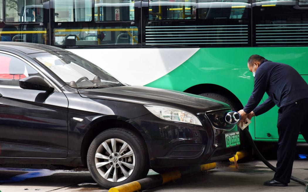 (220512) -- QINGDAO, May 12, 2022 (Xinhua) -- A driver charges an electric car at a shared electric bus charging station in Qingdao, east China's Shandong Province, May 11, 2022. Qingdao City has recently opened some electric bus charging stations to the public. Private vehicles and ride-hailing cars can share the charging facilities together with the public buses. (Xinhua/Li Ziheng) (Photo by Li Ziheng / XINHUA / Xinhua via AFP)
