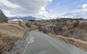 A street view of Dennison Way, it looks rural and there are snow-capped mountains in the distance.