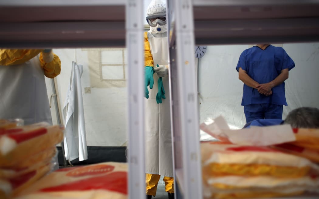 A worker adjusts her gloves as she learns to put on her protective suit during an Ebola training session in Spain.