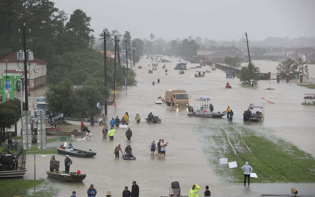 People walk down a flooded street as they evacuate their homes after the flooding.