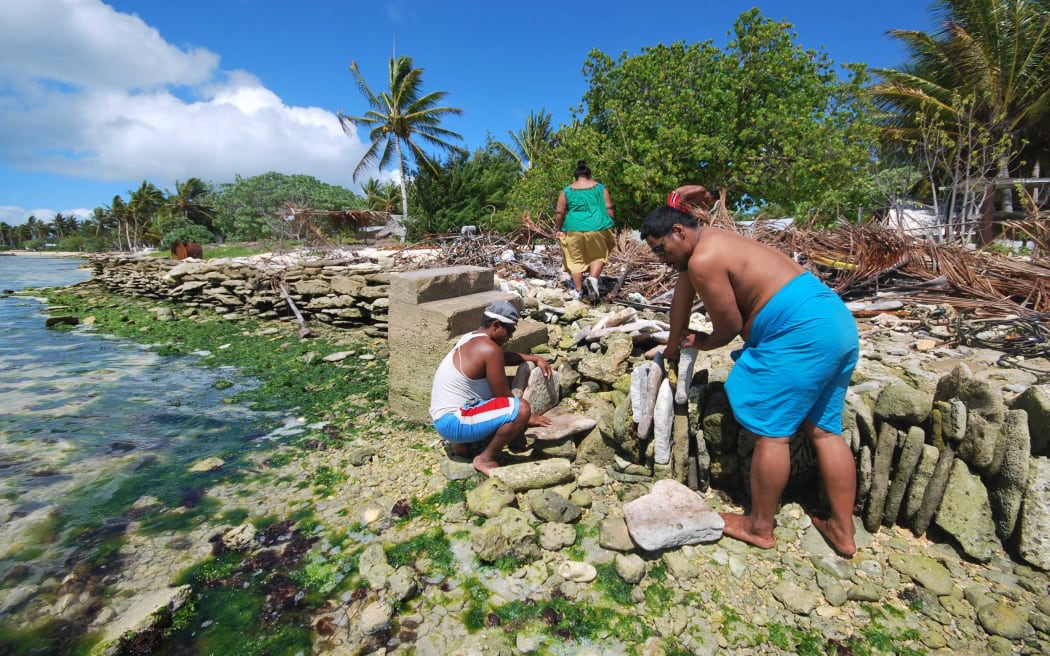 People of Kiritimati coral atoll building a stone seawall to struggle against sea level rise cause by global warming.