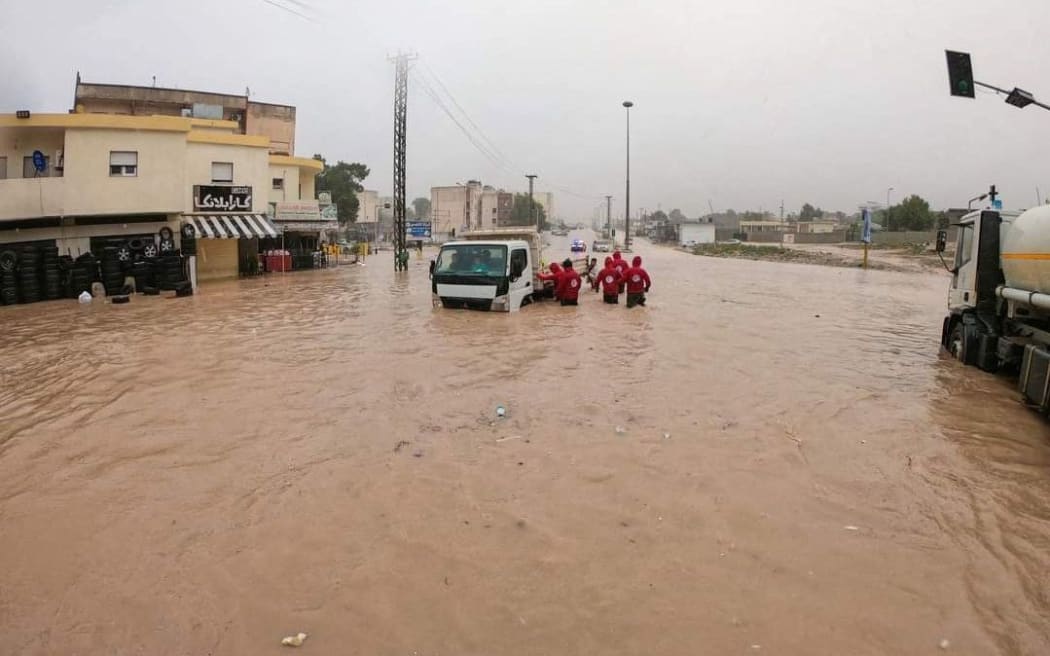 This picture released by the Libyan Red Crescent on September 11, 2023, shows members of their team working on opening roads engulfed in floods in al-Bayda town in eastern Libya.