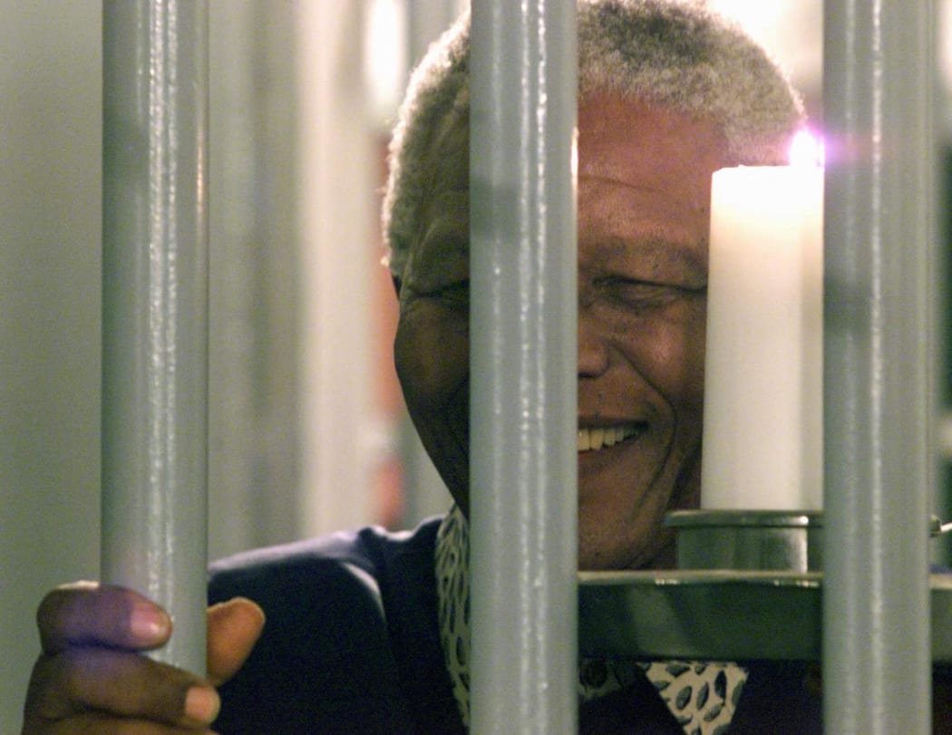Former South African President Nelson Mandela holds a symbolic millennium candle 31 December 1999 in his cell at the prison of Robben Island where he was imprisoned for 27 years during the apartheid time.