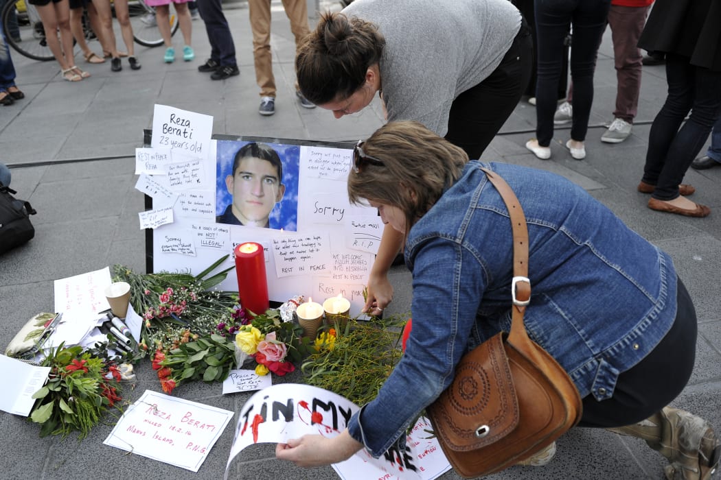 People places flowers and cards next to the portriat of Iranian asylum seeker Reza Berati during a candlelight vigil in support of asylum seekers, in Melbourne on February 23, 2014.