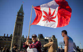 A file photo of a woman waving a flag showing a marijuana leaf, as a group celebrates National Marijuana Day in Ottawa in 2016.