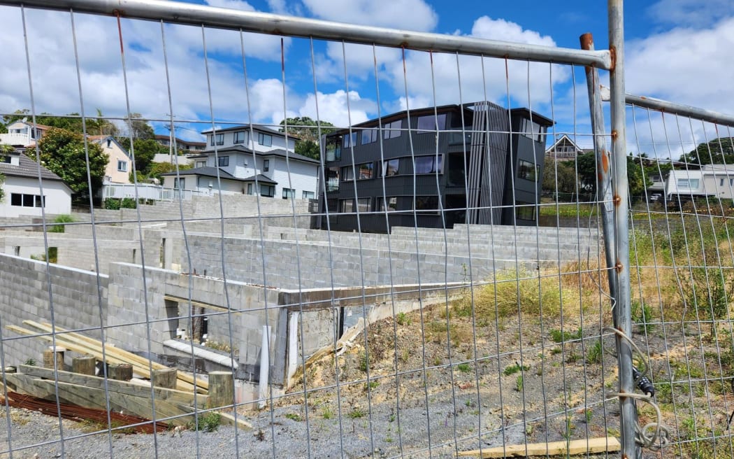 Large concrete slabs can be seen in front of town houses and behind an ageing wire fence.