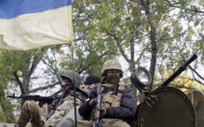 Ukrainian servicemen sit atop of an armored personnel carrier as they patrol in Donetsk region.