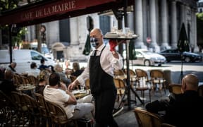 A masked waiter works at the terrace of the Cafe de la Mairie on the Place Saint-Sulpice in Paris on June 2, 2020, as cafes and restaurants reopen in France.