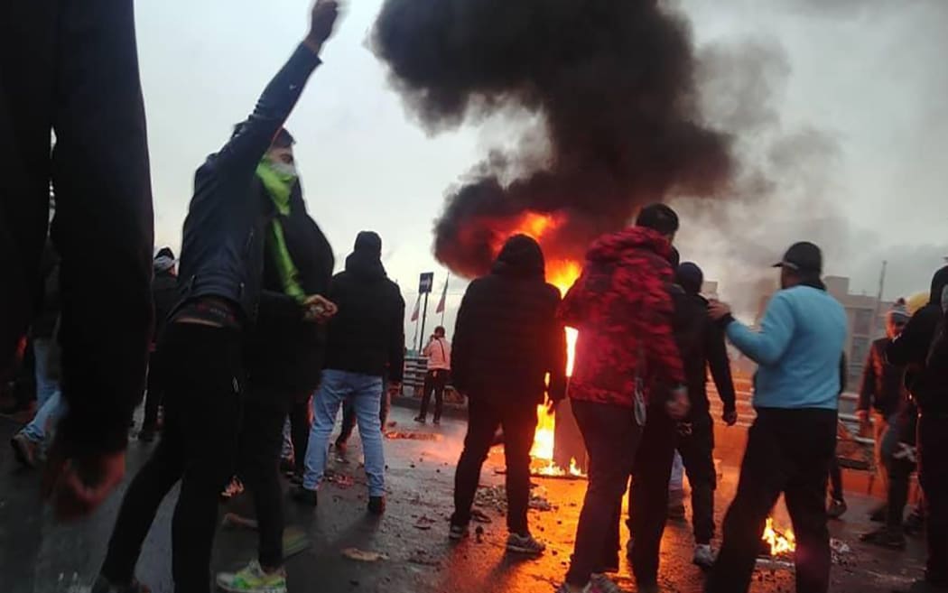 Iranian protesters gather around a fire during a demonstration against an increase in gasoline prices in the capital Tehran, on November 16, 2019.