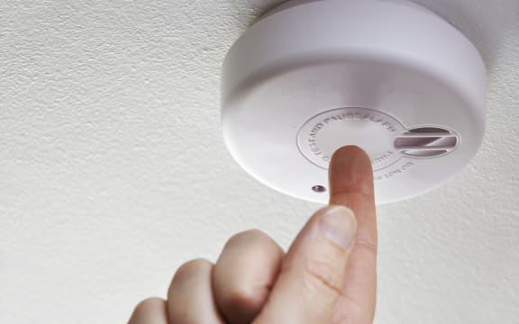Close Up Of Hand Testing Domestic Smoke Alarm