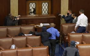 US Capitol police officers point their guns at a door that was vandalised in the House Chamber during a joint session of Congress on January 06, 2021 in Washington, DC.