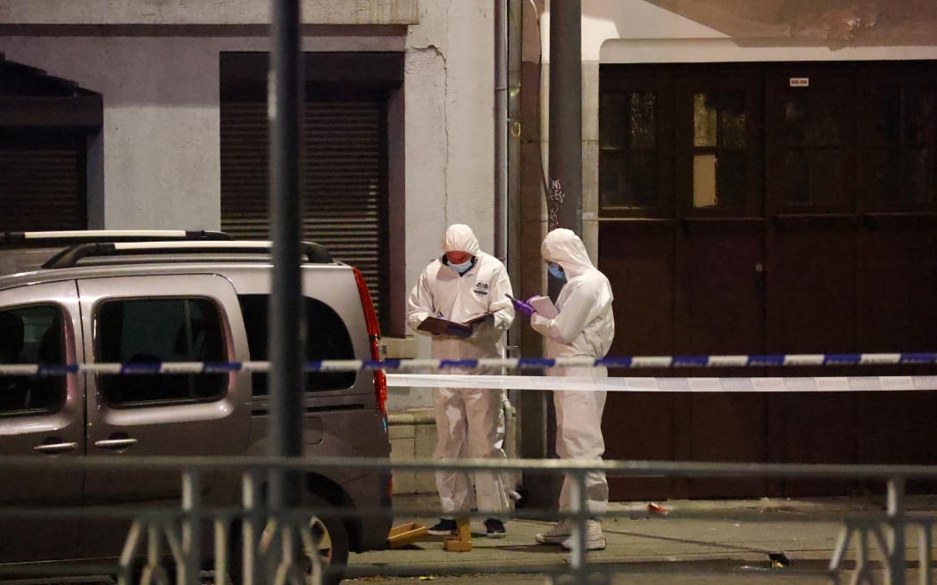 Belgian police officers from the forensic service search for evidence in a street after two people were killed during a shooting in Brussels on October 16, 2023 evening by a suspect who is on the run, the Belgian capital's prosecutor's office said. The alleged gunman in a fluorescent orange jacket fled the scene after using an automatic rifle, according to a video shared by Flemish newspaper Het Laatste Nieuws. A spokeswoman for the prosecutor's office said an investigation had been opened but did not speculate on the gunman's motive. (Photo by Kenzo TRIBOUILLARD / AFP)