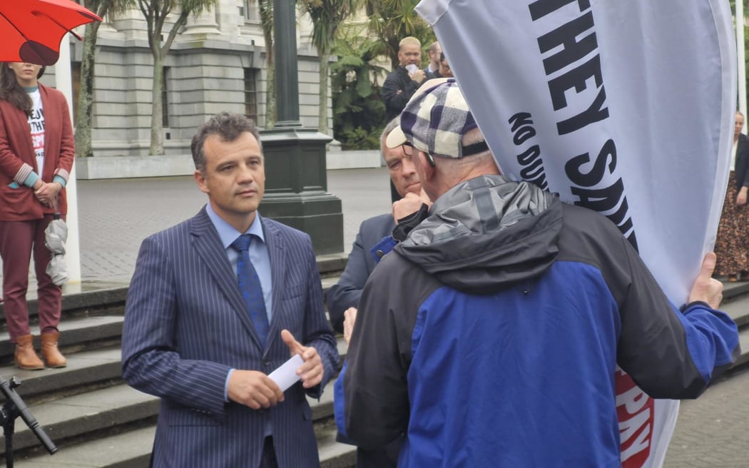 A petitioner steps forward from the protest line to confront National's MP for Southland Joseph Mooney over the government's plans for the Dunedin Hospital build, during Mooney's speech on the forecourt at Parliament.