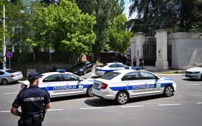 Police cars and officers are stationned on a street around the Israeli embassy in Belgrade, on June 29, 2024. A man wielding a crossbow shot and wounded a police officer guarding the Israeli Embassy, before being fatally shot in return by the guard officer, officials said. (Photo by OLIVER BUNIC / AFP)