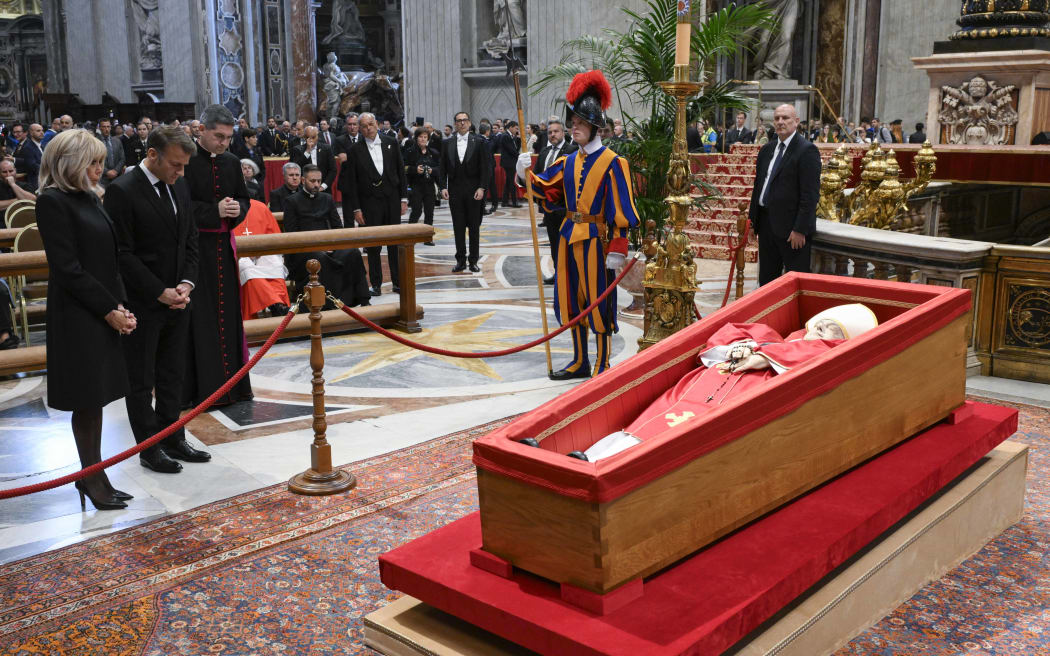 This photo taken and handout on April 25, 2025 by The Vatican Media shows France's President Emmanuel Macron (2ndL) and his wife Brigitte Macron (L) paying their respects to late Pope Francis as he lies in state at St Peter's basilica in The Vatican. The public viewing of Pope Francis's open coffin ended on April 25, 2025, television footage showed, after more than 150,000 worshippers had paid respects to the Argentinian pontiff during a three-day lying in state. (Photo by Handout / VATICAN MEDIA / AFP) / RESTRICTED TO EDITORIAL USE - MANDATORY CREDIT "AFP PHOTO / VATICAN MEDIA" - NO MARKETING - NO ADVERTISING CAMPAIGNS - DISTRIBUTED AS A SERVICE TO CLIENTS