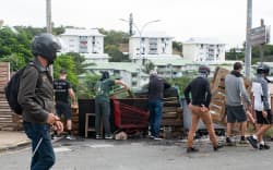 Masked residents of neighborhoods south of the capital, set-up roadblocks to block access and channel pro-independence activists at the entrance to Tuband, in the Motor Pool district of Noumea on May 15, 2024, amid protests linked to a debate on a constitutional bill aimed at enlarging the electorate for upcoming elections of the overseas French territory of New Caledonia. One person was killed, hundreds more were injured, shops were looted and public buildings torched during a second night of rioting in New Caledonia, authorities said Wednesday, as anger over constitutional reforms from Paris boiled over. (Photo by Delphine Mayeur / AFP)