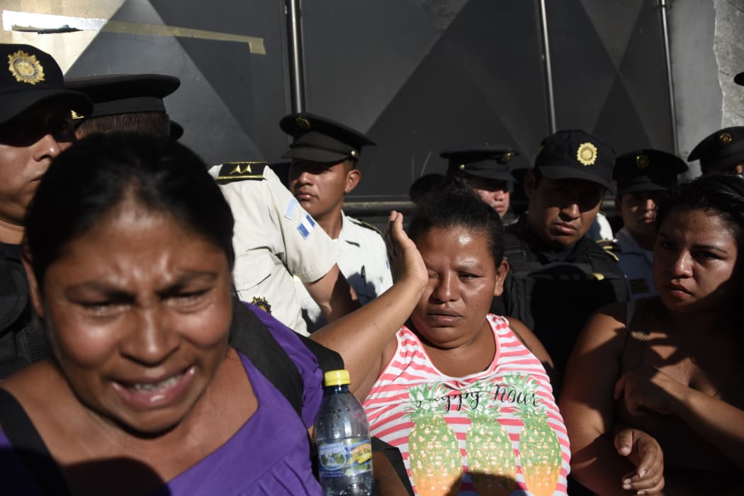 Relatives cry outside the children's shelter Virgen de la Asuncion, guarded by police, after a fire at the facility killed at least 19 people, in San Jose Pinula, 10 km east of Guatemala City, on 8 March.