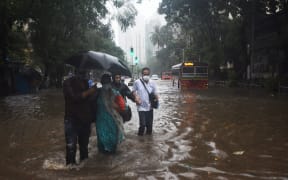 People walking on a flooded road as Cyclone Tauktae brings heavy rain to  Mumbai on 17 May 2021.