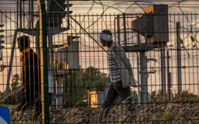Migrants who successfully crossed the Eurotunnel terminal walk on the side of the railroad in Frethun,northern France as they try to reach a shuttle to Britain.