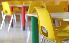 A file photo shows bright yellow chairs in a kindergarten or pre-school.