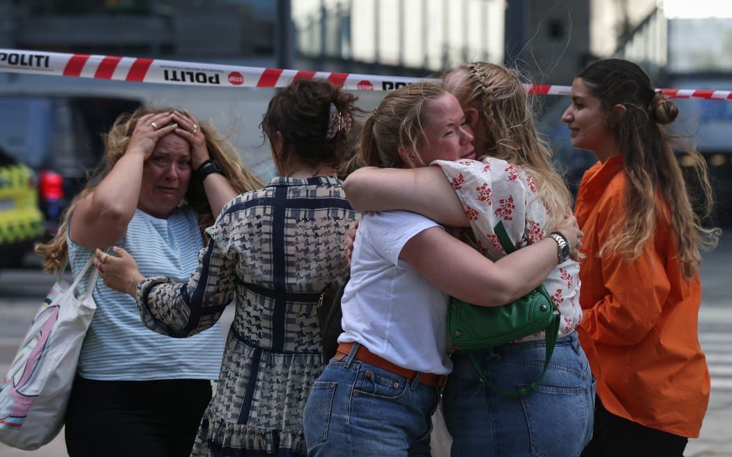People embrace as police evacuate of the Fields shopping center in Copenhagen, Denmark, on July 3, 2022 after Danish media reported a shooting. - Gunfire in a Copenhagen mall left "several dead," and several wounded Danish police said. (Photo by Olafur Steinar Gestsson / Ritzau Scanpix / AFP) / Denmark OUT
