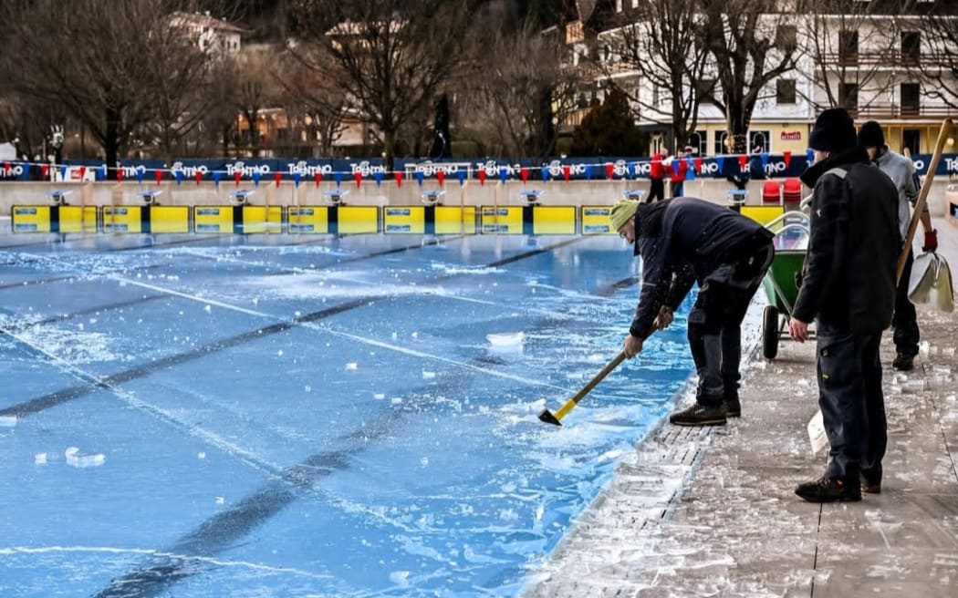 Event staff break up ice which covered the competition pool