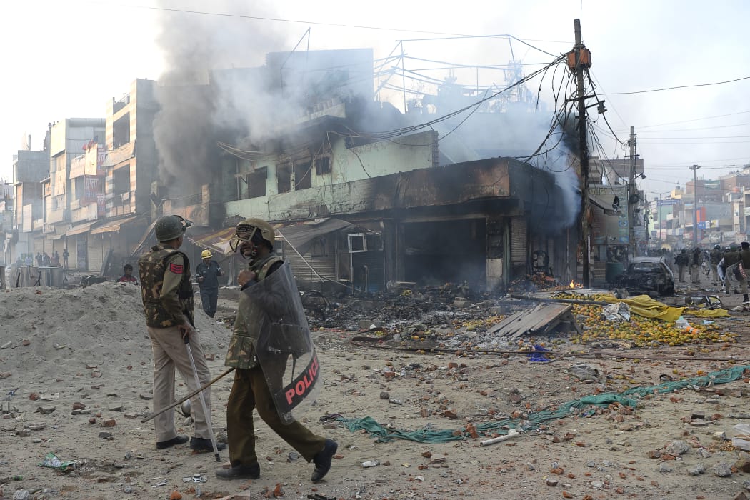 Police officers in front of vandalised shops following clashes between supporters and opponents of a new citizenship law, at Bhajanpura area of New Delhi.