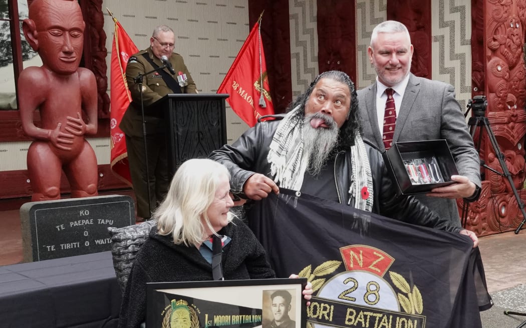 Karen Fletcher and Theo Bunyan, performing a pukana, accept medals for 28th Māori Battalion veteran John Bunyan presented by Te Tai Tokerau MP Kelvin Davis.