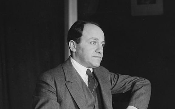 composer Ernest Bloch sitting at a table staring into space