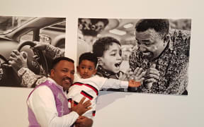 Niguisse Fenja with his photos and son Emmanual.