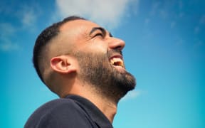 man smiling in profile with blue sky behind