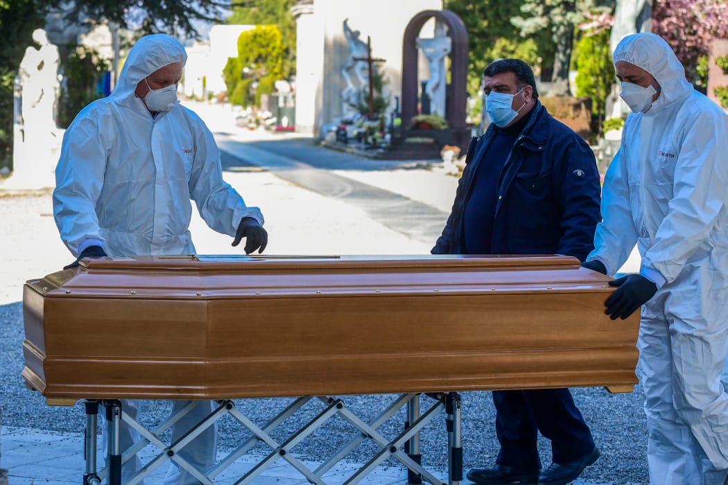 Undertakers unload a coffin at the Monumental cemetery of Bergamo, Lombardy, as burials of people who died of the new coronavirus are being conducted one every half hour.
