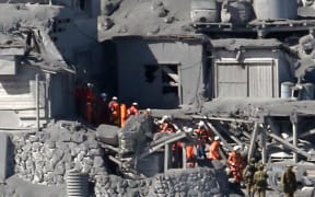 Rescue workers and soldiers searching for missing climbers and survivors in ash-covered cottages on Mount Ontake.