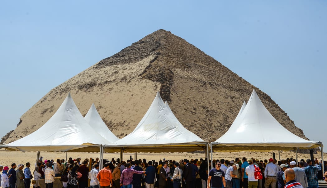 People gather during an inaugural ceremony in front of the Bent pyramid of King Sneferu, the first pharaoh of Egypt's 4th dynasty, in the ancient royal necropolis of Dahshur  south of  Cairo on July 13, 2019.