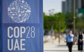 People walk past a COP28 logo ahead of the United Nations climate summit in Dubai on 28 November 28, 2023.