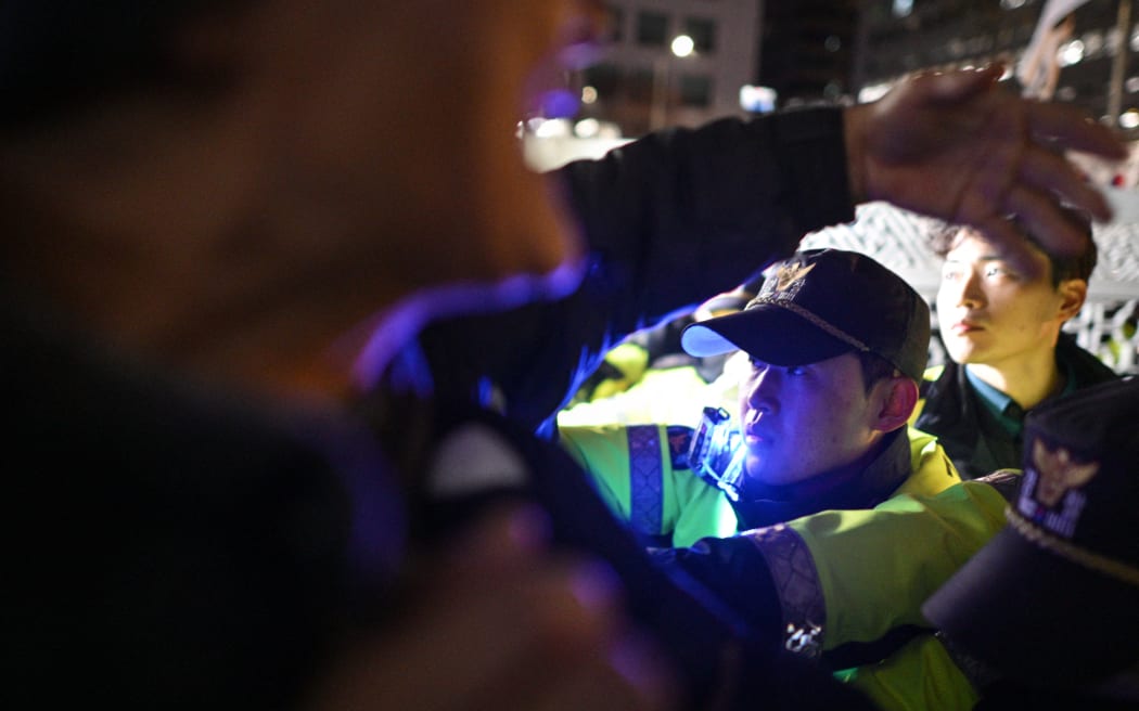 Police hold back people trying to enter the National Assembly in Seoul on December 4, 2024, after South Korea President Yoon Suk Yeol declared emergency martial law. - South Korea's President Yoon Suk Yeol on December 3 declared emergency martial law, saying the step was necessary to protect the country from "communist forces" amid parliamentary wrangling over a budget bill. (Photo by Anthony WALLACE / AFP)