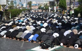 Pakistani Shiite Muslim devotees offer Friday prayers during the procession.