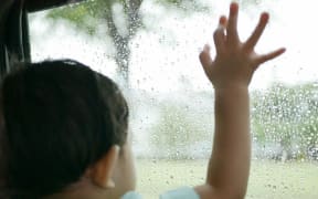 A toddler looking out the window.