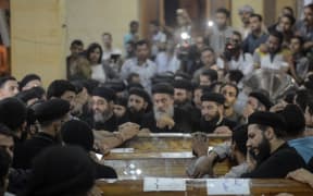 Relatives of killed Coptic Christians grieve by the coffins during the funeral at Abu Garnous Cathedral in the north Minya town of Maghagha