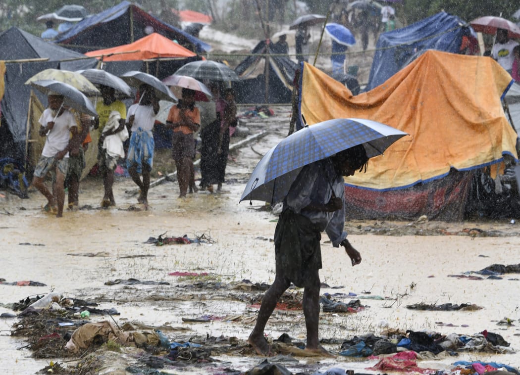 (FILES) In this file photo taken on September 17, 2017 a Rohingya refugee holds an umbrella during heavy rain in Bangladesh's Balukhali refugee camp.
